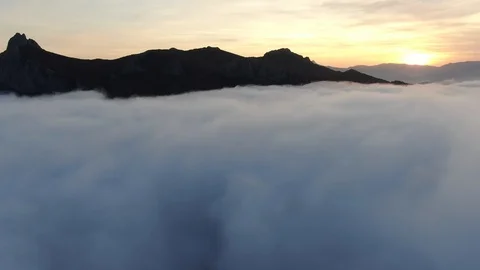 AERIAL Flying from left to right over the clouds with mountain range and sunset Stock Footage 120590240