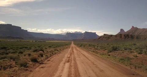 Aerial flying low down a red dirt road in Castle Valley Utah desert mountains Stock Footage 107117126