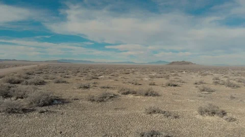 Aerial-Flying low over sparse desert vegetation toward extinct volcano Stock Footage 99985078