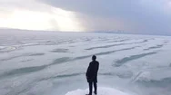 Aerial Flying Near Young Man Standing Victoriously On Pier To The Iced Lake. Stock Footage