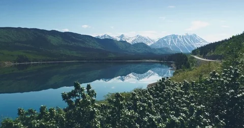 AERIAL: Flying over calm lake, forest and mountains  in Yukon, Alaska, USA Stock Footage