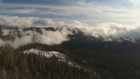 Aerial flying over a forest with light snow below. Incredible clouds and light. 库存影片 128532482