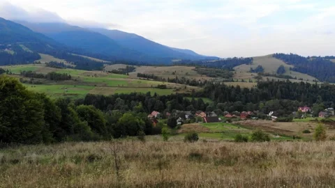 Aerial flying over green fields meadows of mountain valley with dark storm cloud Stock Footage 149838013