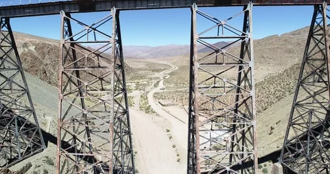Aerial flying over old train metal bridge, in desertic mountainous valley 스톡 동영상 126605769