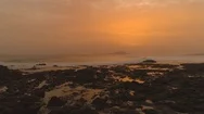 Aerial: Flying Over Rocky Coastline And Foamy Waves At Beautiful Orange Sunset Stock Footage