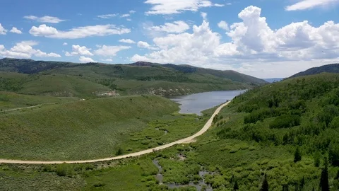 Aerial-Flying over small stream Gravel road to high mountain Lake-POV Vídeo Stock 112363796