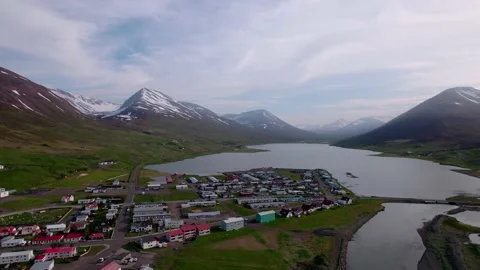Aerial flying over small town with snow covered mountains in the distance. Video stock 166358909