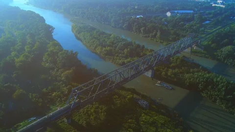 Aerial flying over a train passsing by a bridge above the river. 4K Stock Footage 116485826