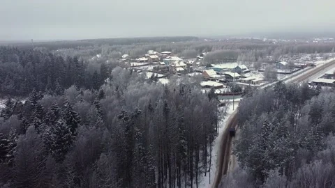 Aerial: Flying over a winter forest and a road near a country village Stock Footage 145154686