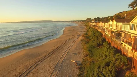 Aerial flying shot down a beach in California with beach houses during sunset. Video stock 88422497