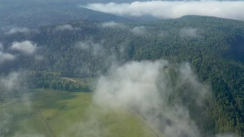 Aerial: Flying through the clouds over picturesque cliffs surrounded by forest. Stock Footage 114720604