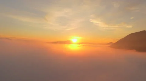 AERIAL: Flying through the clouds toward amazing golden sun at sunrise Stock Footage 65133653