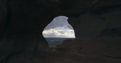 Aerial flying through stone arch to dramatic sky and desert beyond Stock Footage 111360601
