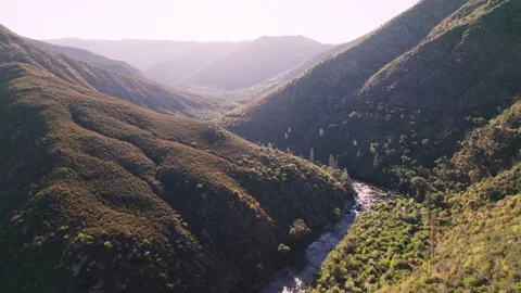 Aerial flying through a valley with a river running below. Shot in California. Video stock 228647906