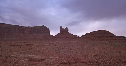 Aerial: flying toward "The Sitting Hen" in Monument Valley with purple clouds Video stock 100613202