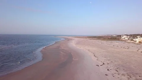 Aerial flyover of empty beach with two people walking along the water. Stock Footage 88145121