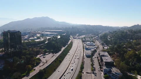 Aerial flyover of a freeway near Universal City through a wooded canyon pass Video stock 343615480