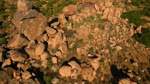Aerial flyover of large boulder rock formations in the desert Stock Footage 79353492