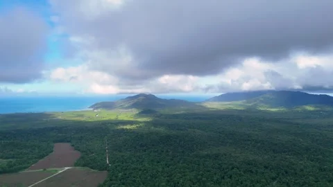Aerial Flyover of Lush Rainforest and Farmland Under Clouds Stock Footage 314043916