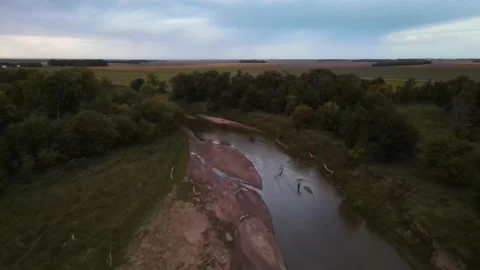 Aerial flyover of murky river surrounded by lush greenery and cultivated fields. Stock Footage 157767974