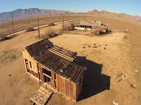 Aerial flyover of old farm building in the desert Stock Footage