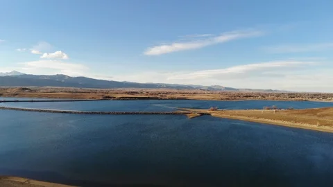 Aerial Flyover of a Reservoir and Rocky Mountains at Sunset Stock Footage