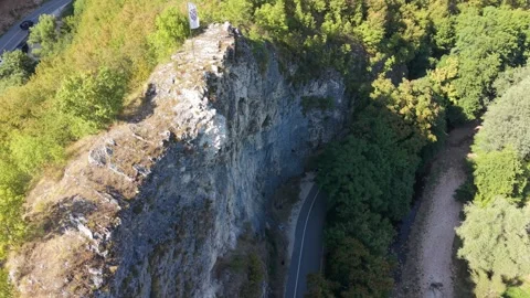 Aerial Flyover of Rock Face with Fleur-de-Lis Flag Above Dariva Showing Road Stock Footage 342715986