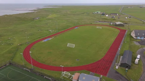Aerial Flyover Of Running Track Surrounded By Buildings And Coastal Land Video stock 340421688