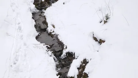 Aerial flyover a small stream in winter, snow covered ground. Stock Footage 72773466