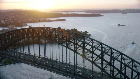 Aerial flyover of Sydney Harbour Bridge, morning sun rising over horizon Stock Footage