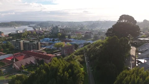 Aerial Flyover Treetops with Dramatic Sunbeams Revealing Puerto Montt City and B Stock Footage 324262782