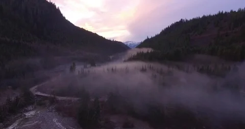 Aerial of foggy mountain valley River and forest during dawn Stock Footage