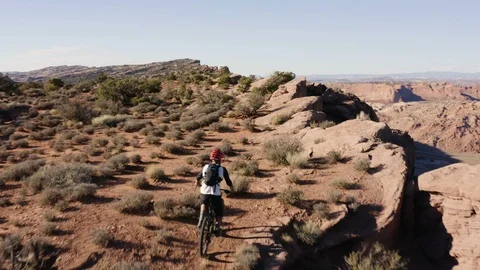 Aerial Follow Shot Of A Man Biking Through The Desert On The Edge Of A Cliff Video stock 100516341