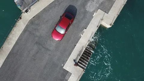 Aerial following car top-down view the car is on the pier surrounded by yachts. Stock Footage 106405853