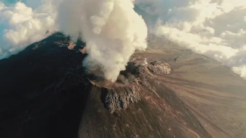 Aerial footage of active volcano emitting massive smoke plume above clouds Stock Footage 345484418