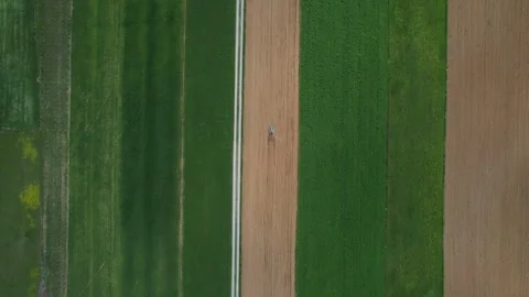 Aerial footage capturing farmer operating small crawler tractor, creating Stock Footage 306329005