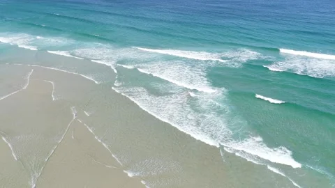 Aerial footage capturing the turquoise waves rolling onto the sandy shore of Stock Footage 346708342