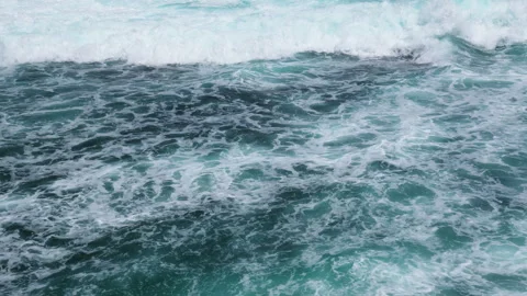 Aerial footage of dynamic ocean surface with rolling waves and sea foa. Stock Footage 303370815