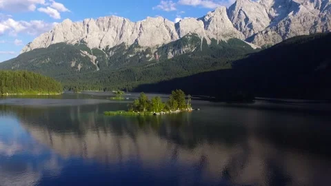 Aerial footage of lake Eibsee beneath Zugspitze peak with small islands. Stock Footage