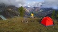 Aerial Footage Of A Man Standing Near A Tent In Front Of Mountain Valley. Stock Footage