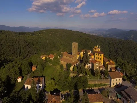 Aerial footage of a small village among green hills and plain landscape Stock Footage