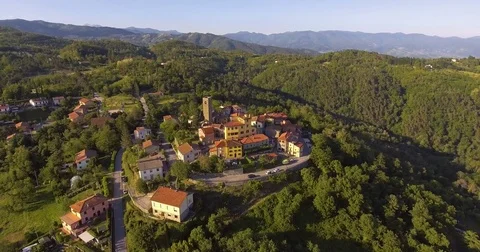 Aerial footage of a small village among green hills and plain landscape in Tu Stock Footage