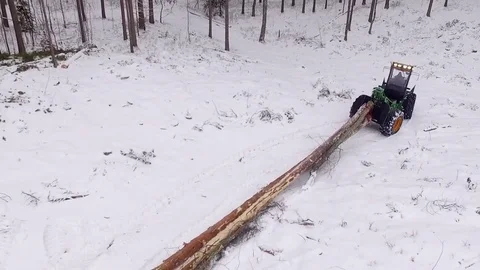Aerial footage of a tractor pulling a tree in the forest in winter Stock Footage 69967946