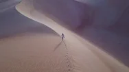 Aerial Footage Of A Woman Walking On A Sand Dune During Sunrise. Stock Footage