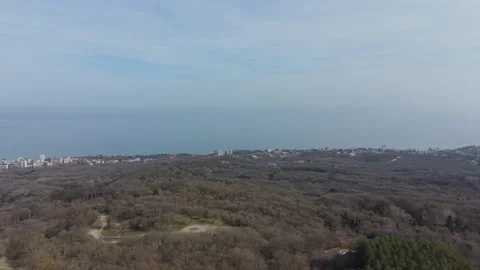 Aerial forest landscape with distant town surrounded by rolling hills Видео 331424736