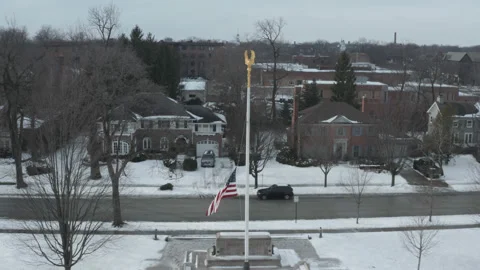 Aerial forward on half staff flag monument in snowy midwest neighborhood park Stock Footage 211188916
