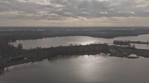 Aerial forward motion over lake landscape with sun through clouds Видео 330189838
