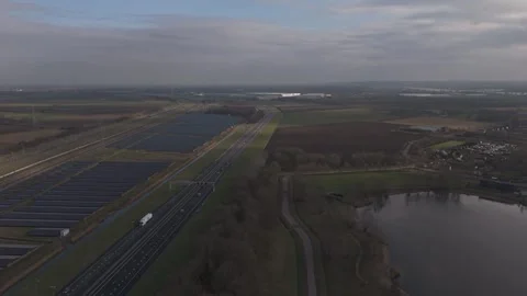 Aerial forward motion over solar farm with highway and railway infrastructure NL Stock Footage 330189817