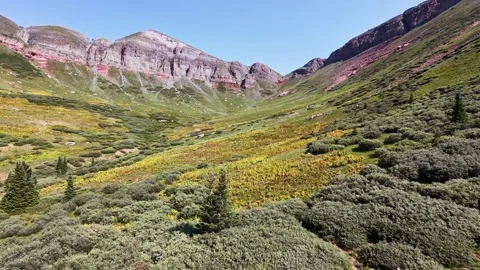 Aerial Forward Rising Flight Through Mountain Valley Meadow with Hiker Waving Stock Footage 342612641