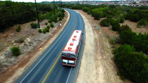 Aerial Forward Shot Of Patterned Tour Bus Moving On Road Amidst Plants In Stock Footage 222030282